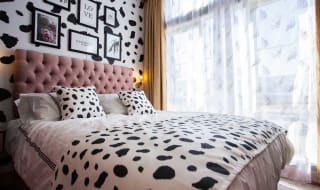 A double bedroom with cow spot print feature wall and continued on the bedding with light pink duvet covers. image