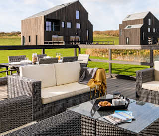 An outside area of one of our luxury barns with outside furniture. Over the balcony are two further lodges.