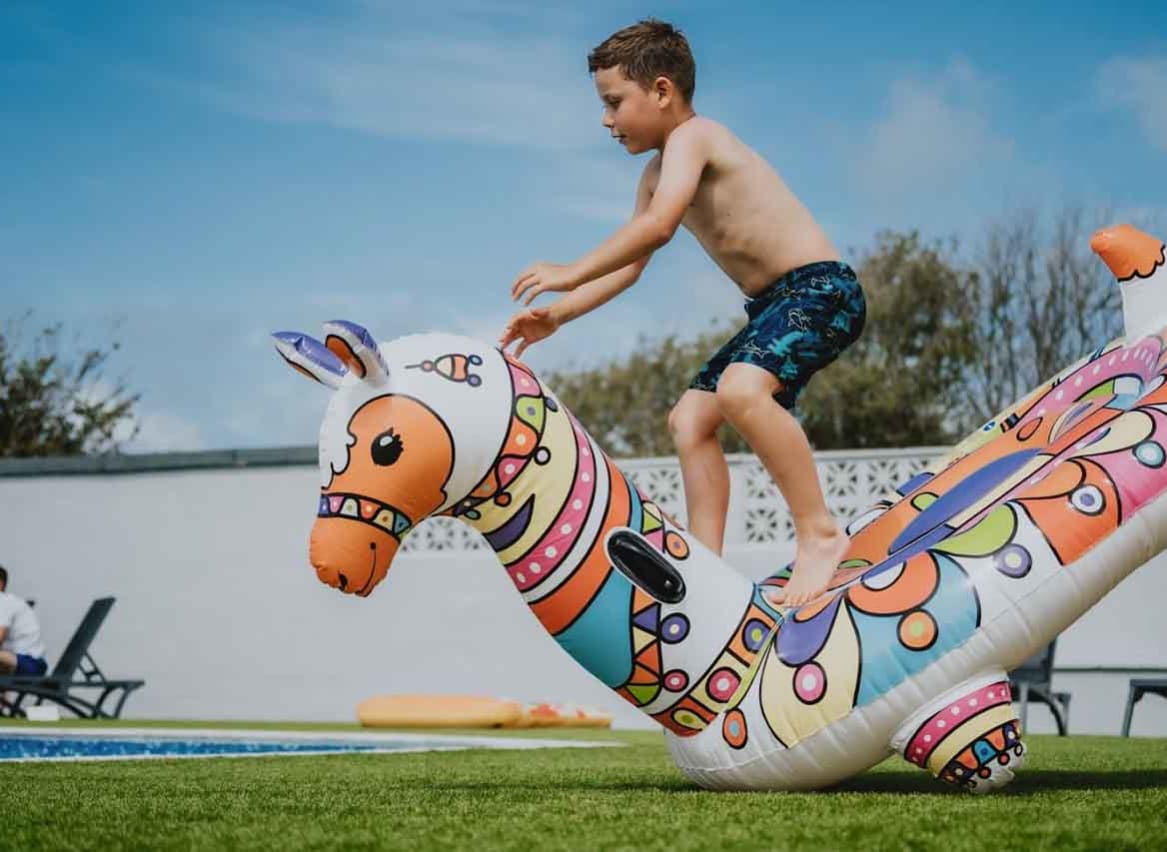 A young white boy, jumping onto an inflatable lama into the outside pool. image