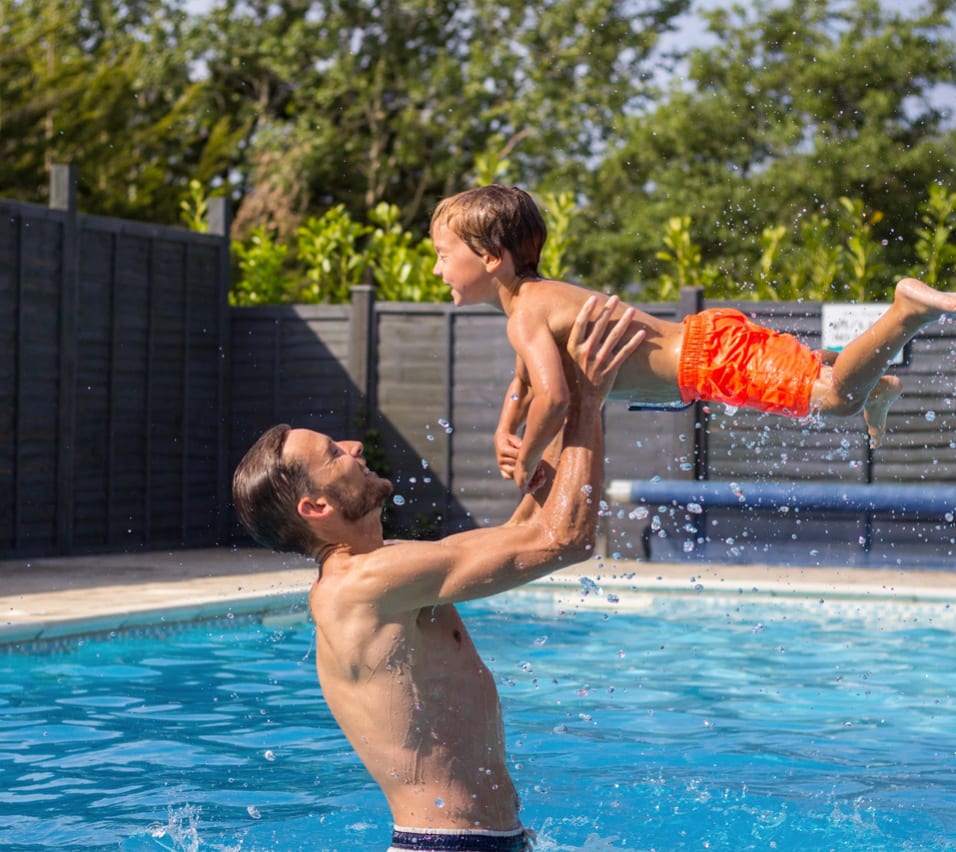A father and son enjoying a splash in the heated outdoor pool at our stunning resort on the Isle of Wight, The Lakes Rookley. image