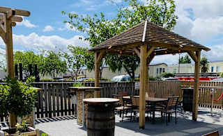 A sunny day with a view of a wooden gazebo covering a set of table and chairs at our holiday park in CLeethorpes Pearl, Lincolnshire. image