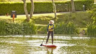 A woman paddleboarding on a sunny day through the lake at our Isle of Wight holiday park, The Lakes Rookley.