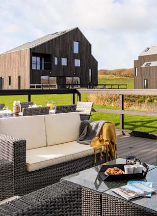 An outside area of one of our luxury barns with outside furniture. Over the balcony are two further lodges.