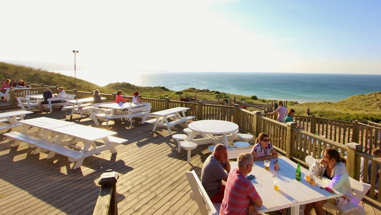 The outdoor eating area of our restaurant at St Ives Bay Holiday Park, with views of the sea.