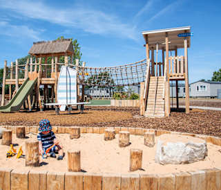 Child playing in the sand at our adventure playground in the sunshine at Mill Rythe Holiday Park, Hampshire.
