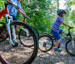 A family out cycling together through the woods.