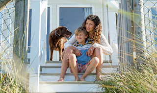 A mother, son and their chocolate lab dog sitting on the steps of one of our static caravans.