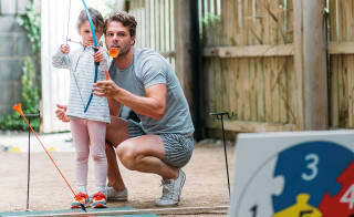 A father and daughter taking part in one of our awesome on-site activities, archery. image
