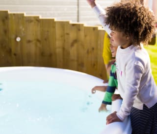 Three young children playing outside one of the hot tubs at our Whitecliff Bay holiday park.