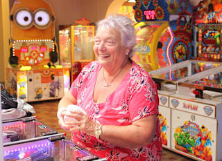 An image of a woman playing in the arcade at Golden Sands. In the background you can see lots of other fun machines. image