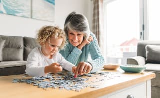 A grandma and granddaughter completing a puzzle together. image