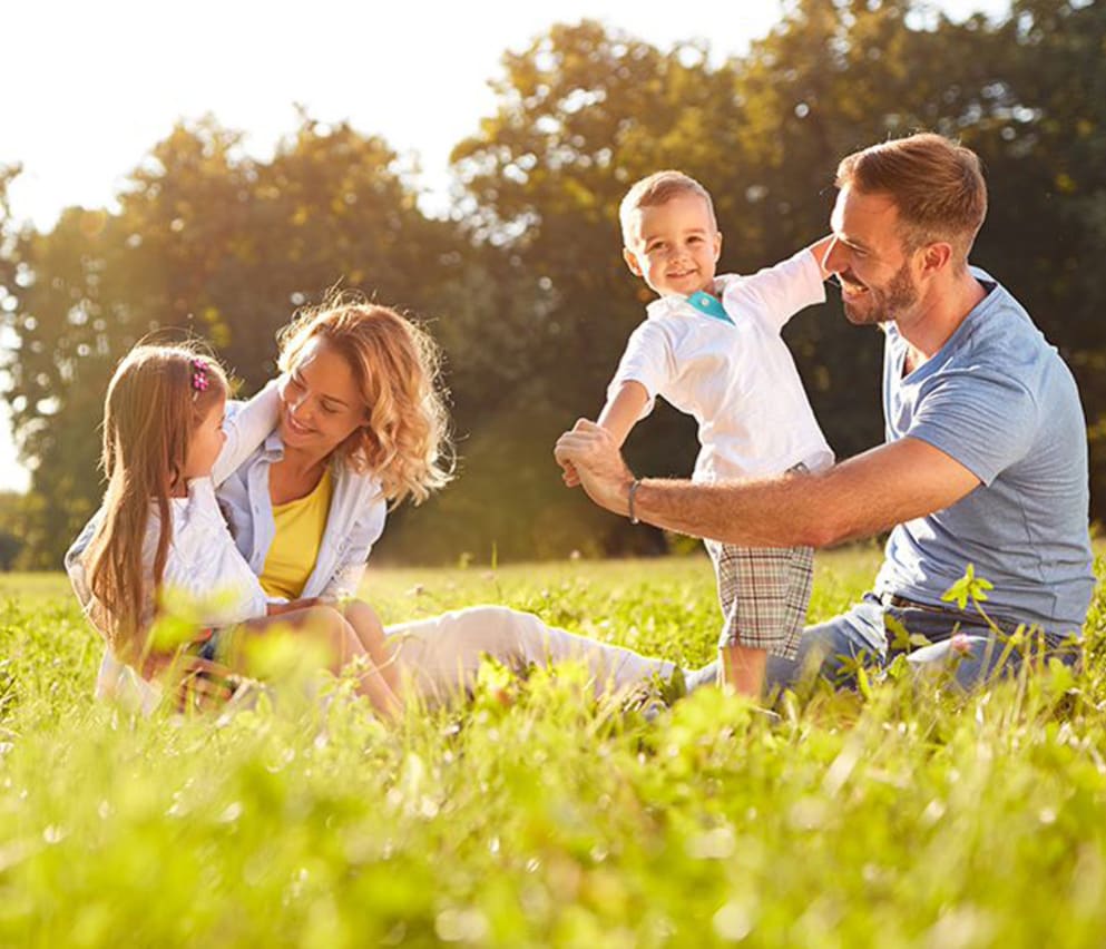 A young family playing in the grass outside on a sunny day.