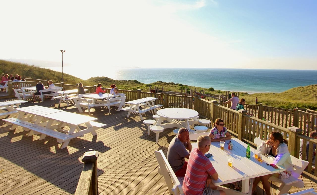 The outdoor eating area of our restaurant at St Ives Bay Holiday Park, with views of the sea. image