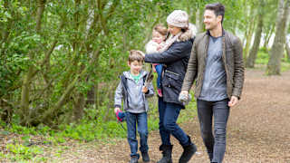 Family of four walking through trees together at Tattershall Lakes.