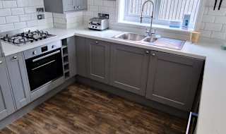 A kitchen within one of our cottages. A U shaped kitchen with clear and clean counter space. Modern grey cabinets and a window above the sink. image