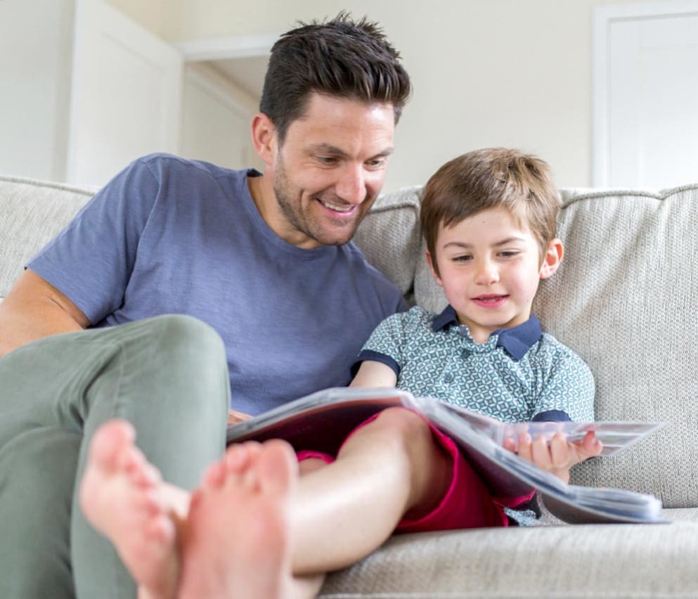 A father and son reading a book together in one of our holiday homes.