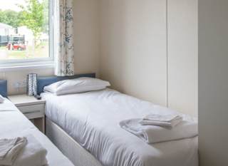 The interior of one of our Indulgent holiday lodges. There's a bedroom with twin beds and a large window. image