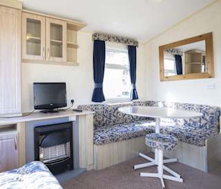 The dining and living area of one of our budget-friendly value static caravans. The perfect way to stay.