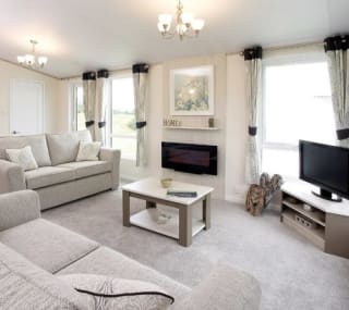 The interior of one of our Luxury holiday lodges. There are two large sofas, a TV, and plenty of space around a coffee table. image