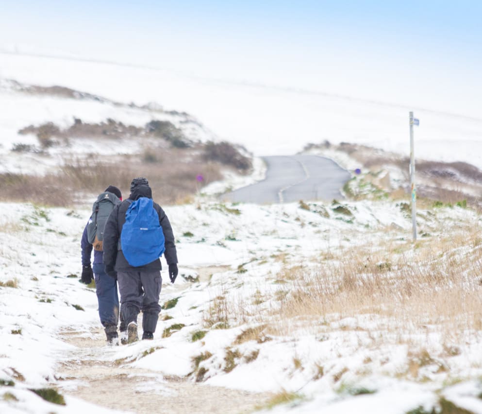 Two people taking a snowy winter walk at our Isle of Wight park, The Bay Colwell.