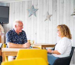 A couple enjoying a drink together at The Muddy Duck Clubhouse at our Essex holiday park, Mersea Island.
