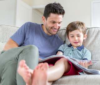 A father and son reading a book together in one of our holiday homes.