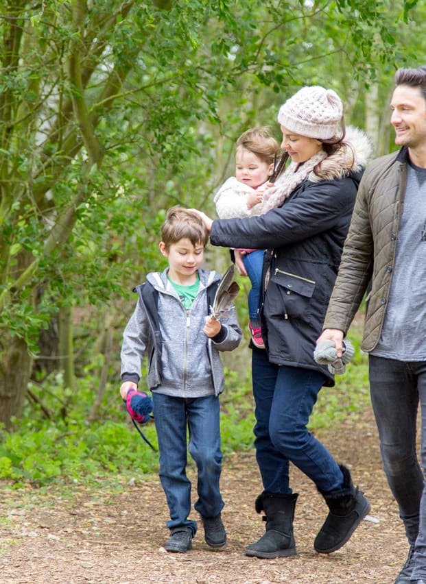 Family of four walking through trees together at Tattershall Lakes.