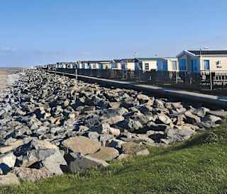 Our Golden Sands holiday park. The long beach stretches far into the distance, with rocks running along one side, and the sea on the other.