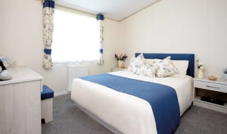 The interior of one of our Luxury holiday lodges. There's a large bedroom with a double bed and window. image