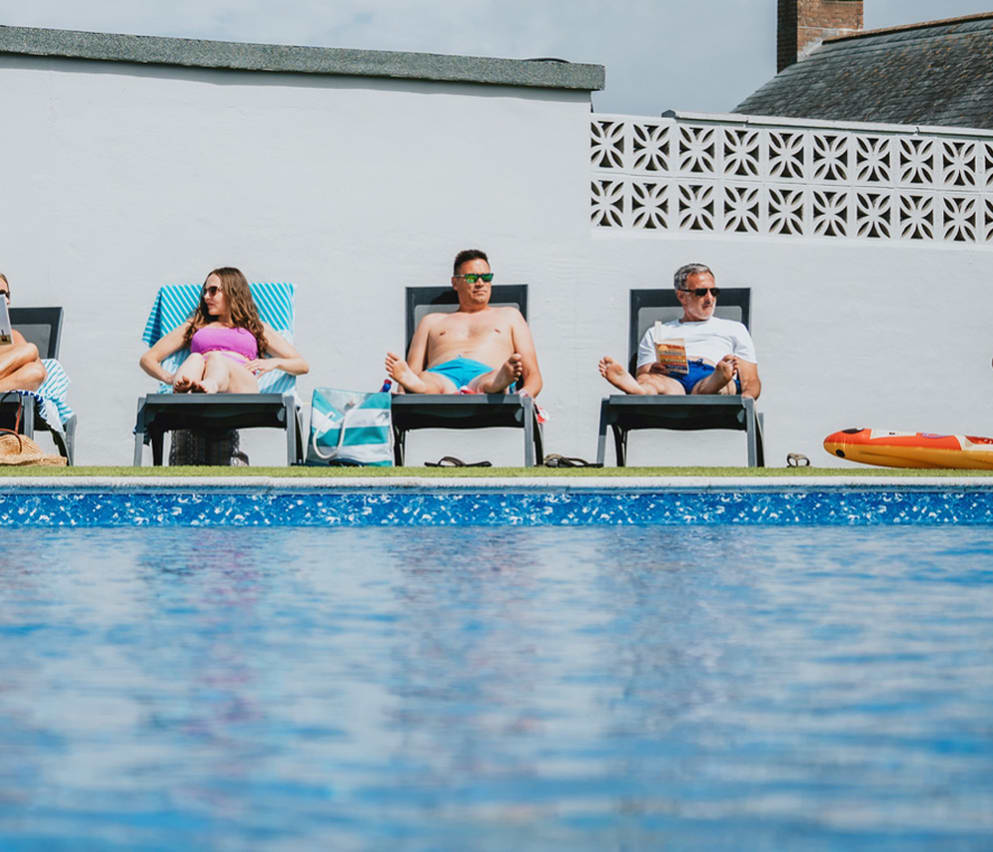 A family enjoying a sunny day at the outdoor heated pool at Bude Holiday Resort.