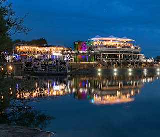 Our Tattershall Lakes holiday park. There is an evening view of the holiday park, with the lights shining bright, and many evening activities taking place in the park.