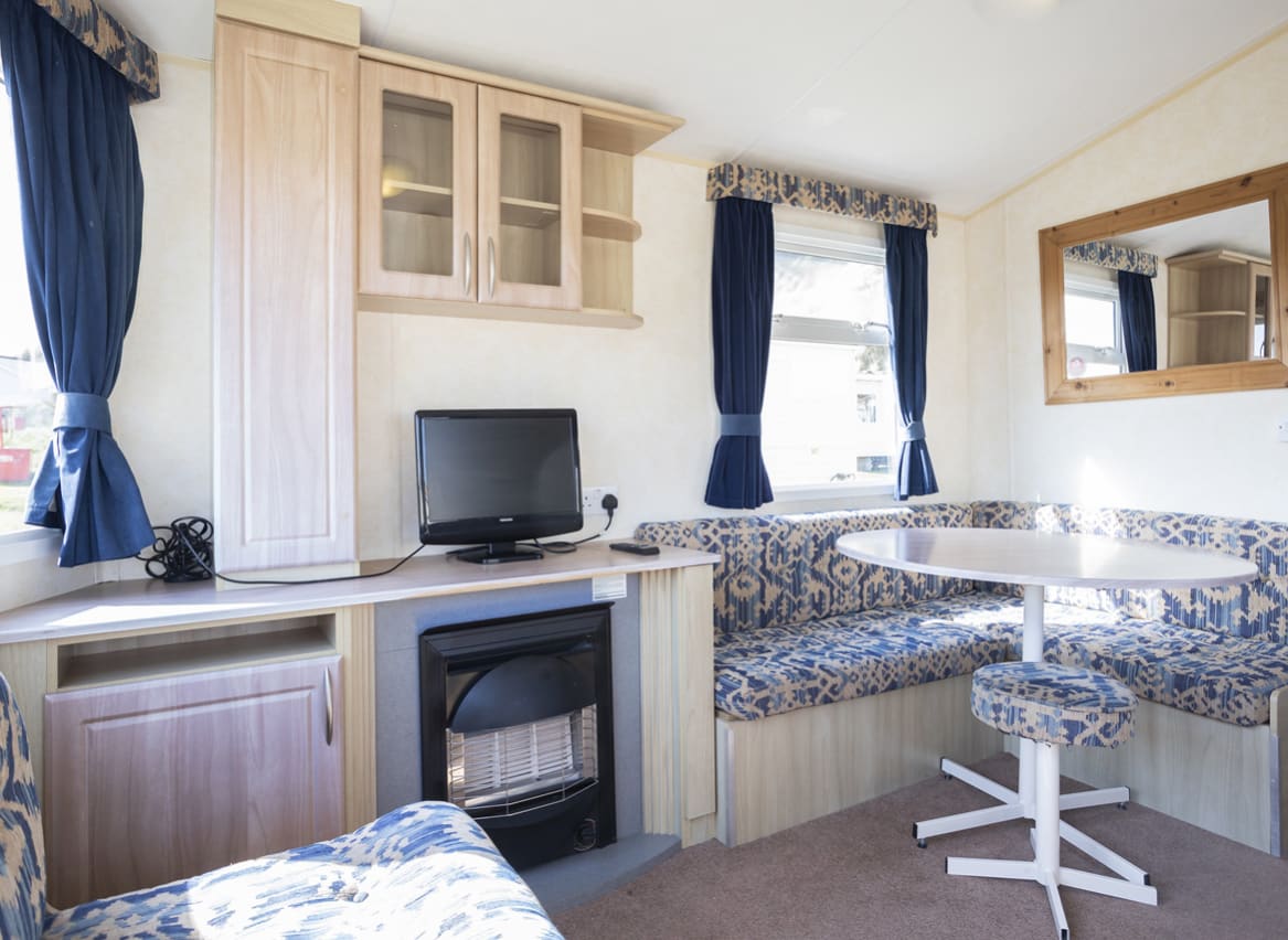 The dining and living area of one of our budget-friendly value static caravans. The perfect way to stay. image
