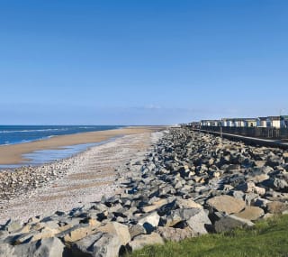 Our Golden Sands holiday park. The long beach stretches far into the distance, with rocks running along one side, and the sea on the other. image