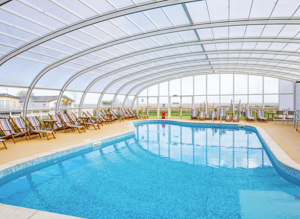 The awesome indoor swimming pool at our holiday park in Essex, Mersea Island. There are multicoloured deck chairs all around the pool. image