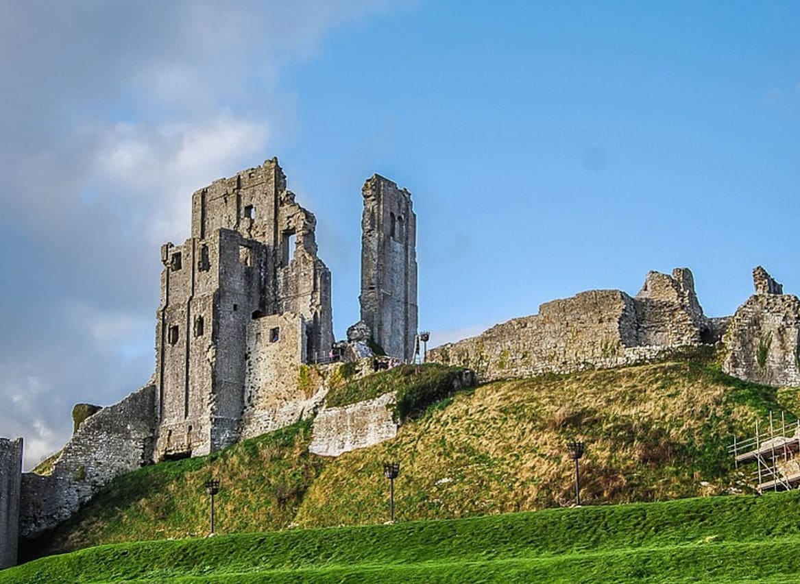 An image of Corfe Castle on a bright day with blue skies. image