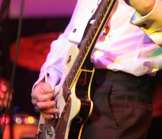 A close up image of a man playing a guitar.