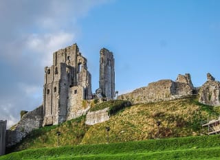 An image of Corfe Castle on a bright day with blue skies. image