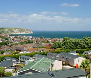 Our holiday park, Swanage Bay View. The bright, sunny day is showing the many holiday homes in the park, along with a view of Dorset, the sea, and the cliffs.
