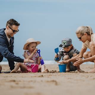 A family enjoying a summers day on the beach. There is a mother and father and two young children. image