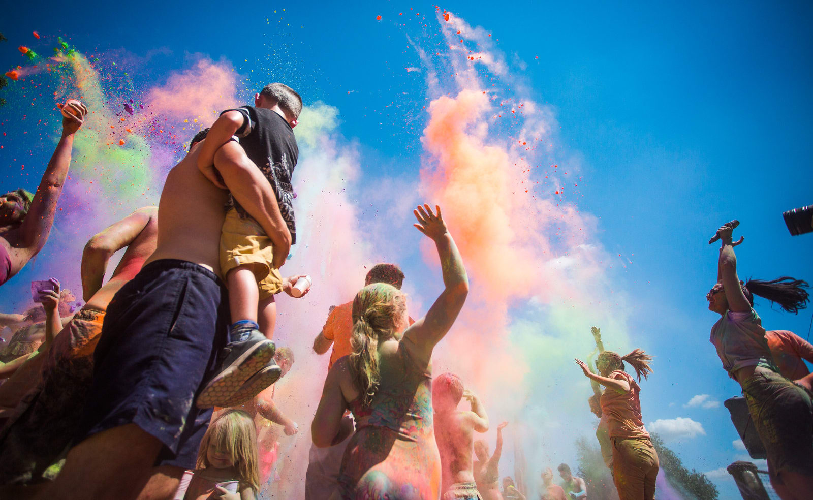 A young family enjoying the colour dash festival on a bright sunny day. We offer this and many more fun events at our Whitecliff Bay holiday park. image