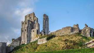 An image of Corfe Castle on a bright day with blue skies.