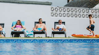 A family enjoying a sunny day at the outdoor heated pool at Bude Holiday Resort.