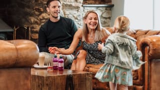 A little girl running towards her mum and dad, who are sat on the sofa in one of our on park restaurants.