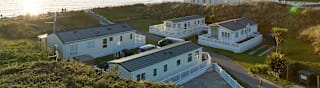 Two rows of caravans with views of the sea and the sun setting at our holiday park in North Wales, Barmouth Bay. image