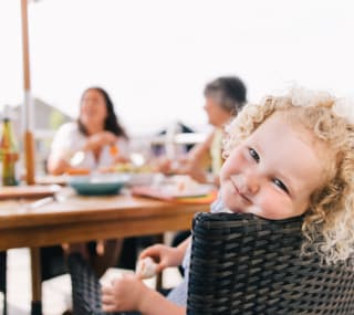 A young girl sat at the table with her family enjoying some lunch on a summers day. image