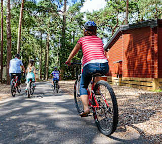 A family cycling together at one of our holiday parks on a sunny day. image