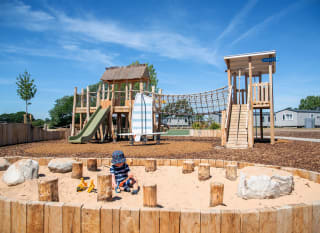 Child playing in the sand at our adventure playground in the sunshine at Mill Rythe Holiday Park, Hampshire. image