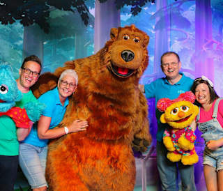 A group of people posing for a photo with the Away Resorts characters, Bear, Scratch and Lucy.
