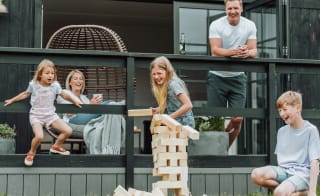 A family of five playing a game of jenga outside their accommodation. image