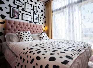 A double bedroom with cow spot print feature wall and continued on the bedding with light pink duvet covers. image